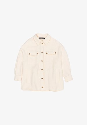 Cremfarbener oversized Jacke aus strukturiertem Stoff. Mit einer Knopfleiste, zwei Brusttaschen und einem Kragen. Goldfarbene Knöpfe als Akzent.