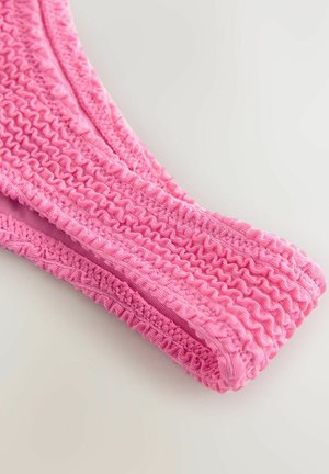 Roze stoffen scrunchie met een gestructureerd, verzameld ontwerp. Elastisch materiaal met kleine ruches en een gladde afwerking.