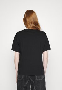 Black cotton T-shirt featuring short sleeves and a relaxed fit, shown from the back with soft texture and simple design.