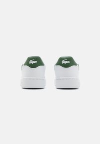 Hvite sneakers med grønne detaljer. Sletten materiale, rund tå, polstret krage og brodert logo på hælen. Minimalistisk design.
