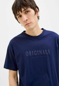 Námořnická modrá bavlněná tričko s kulatým výstřihem a krátkými rukávy, s texturovaným logem "ORIGINALS JACK&JONES" na přední straně.
