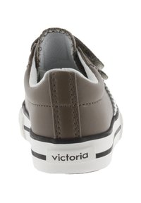 Achteraanzicht van grijze sneaker met witte zool, zwarte streep en 'victoria' logo op de hieltab.