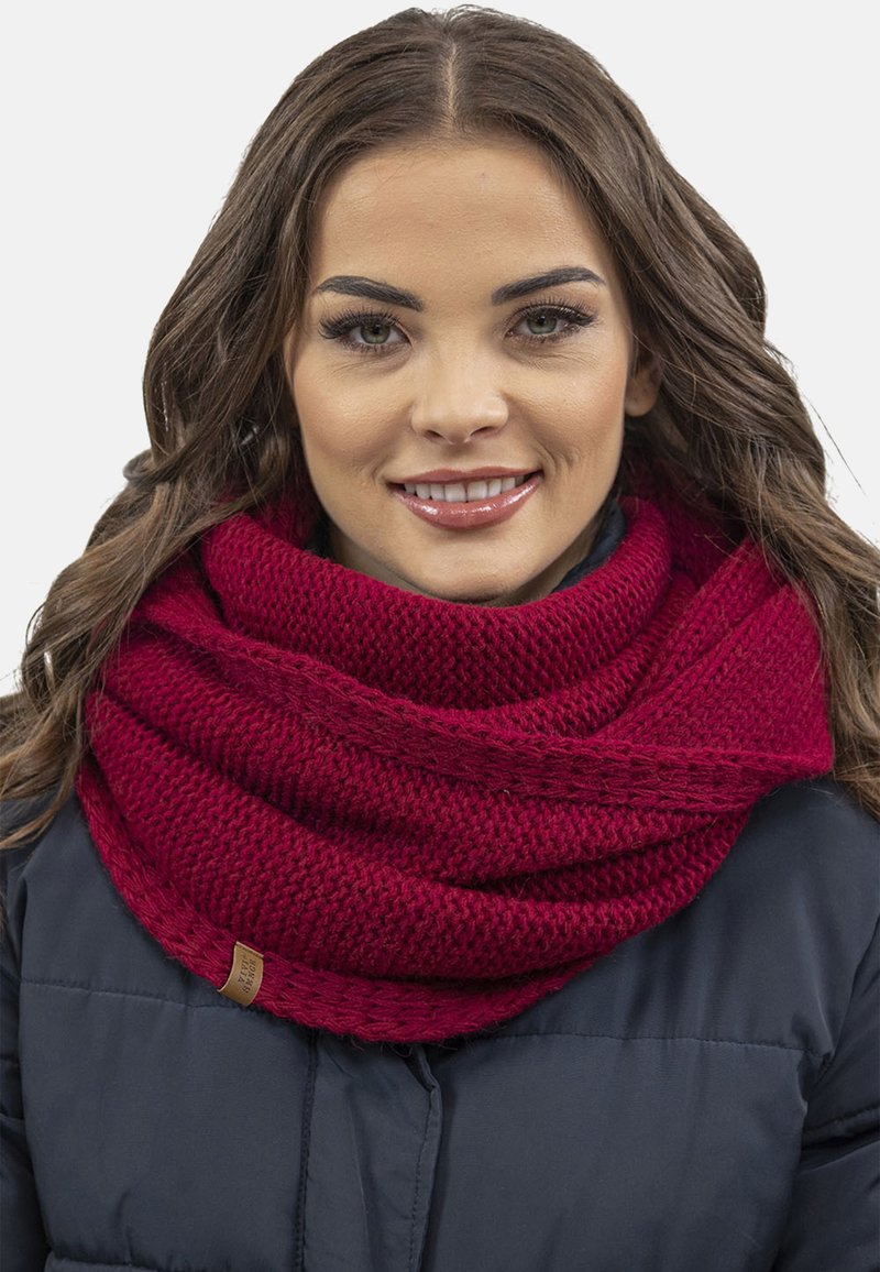 Écharpe en tricot bordeaux avec un motif texturé, enroulée lâchement autour du cou, avec une petite étiquette en cuir.
