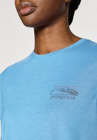 Ανοιχτό γαλάζιο βαμβακερό T-shirt με απλό γραφικό βουνό και τ ο κείμενο «patagonia» από κάτω. Στρογγυλή λαιμόκοψη, ριμπ υφή.