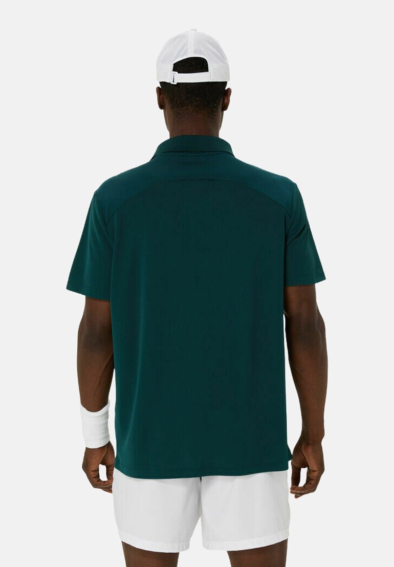 Polo shirt verde scuro, maniche corte, tessuto leggero, vista posteriore, cappellino bianco, braccialetto e pantaloni corti bianchi. Design pulito, senza motivi.