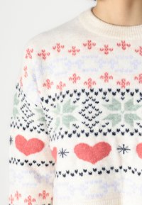 Knit sweater with a cream background featuring red hearts, green leaves, and black details in a patterned design. Round neckline, soft texture.