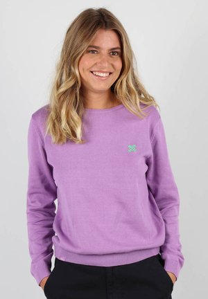 Pull léger en violet pâle avec un col rond, des poignets et un ourlet côtelés, arborant un petit logo vert sur la poitrine. Matière en tricot douce.
