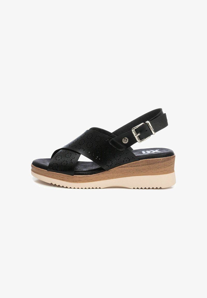 Sandalo con zeppa in pelle nera, design perforato, cinturino regolabile e suola in gomma con un leggero effetto legno.