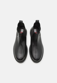 Bottines en cuir noir avec une finition lisse, panneaux latéraux élastiques, tirant à l'arrière et design à bout rond. Semelle en caoutchouc plate.