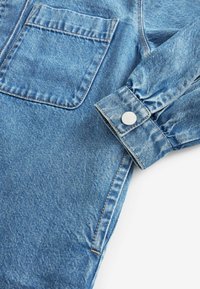 Denimjacke in Hellblau, mit einer Brusttasche, Knopfmanschette und kontrastierenden Nähten. Weicher Stoff mit einem lässigen Design.