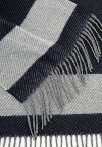 Sciarpa grigia e blu a righe in materiale morbido, con frange sui bordi e un motivo testurizzato con linee diagonali.