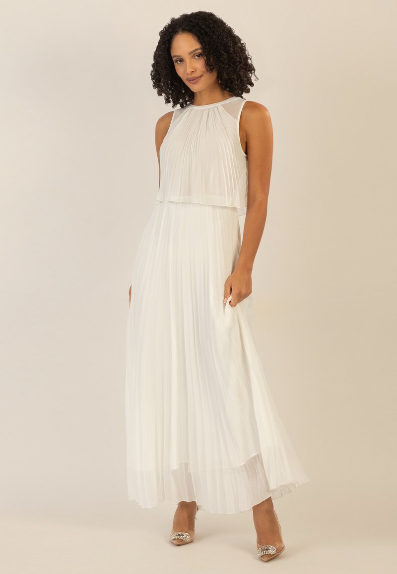 Witte geplooide maxi-jurk met een mouwloos ontwerp en gelaagde lijf. Doorzichtige textuur met een vloeiende silhouet, aangevuld met versierde hakken.