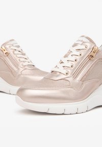 Baskets en rose gold métallique avec des panneaux en maille, des lacets blancs et des fermetures à glissière décoratives sur les côtés. Semelles rembourrées pour un confort et un soutien supplémentaires.
