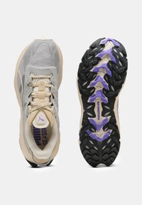 Scarpe da ginnastica grigio chiaro con tomaia in mesh testurizzato, accenti crema e suola nera con dettagli viola e un motivo di battistrada unico.