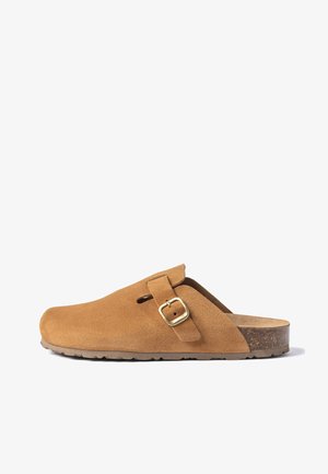 Zueco de ante marrón con correa ajustable y hebilla dorada, plantilla de corcho y suela de goma, mostrado en perfil lateral sobre fondo blanco.