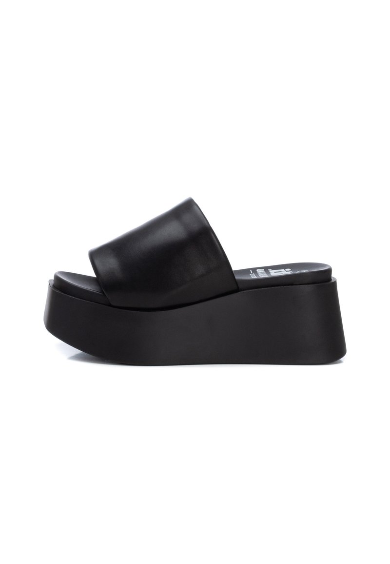 Chanclas de plataforma negras con parte superior de cuero suave, tira ancha y suela de goma gruesa, con un acabado mate y forma contorneada.