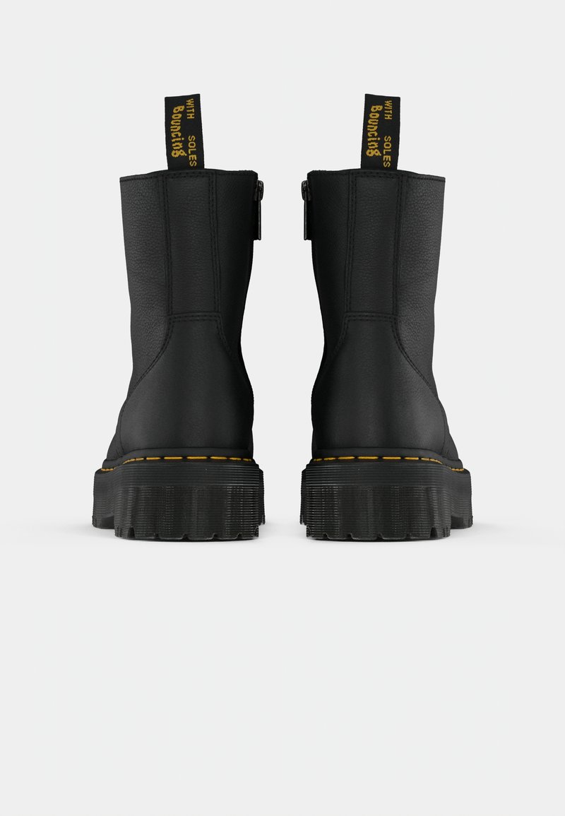 Stivaletto in pelle nera con cuciture gialle e linguette a contrasto, dotato di una suola in gomma chunky e una texture liscia.