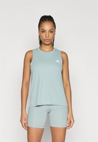 Helehall sinine varrukateta top ümmarguse kaelusega, valmistatud pehmest kangast. Kaasas sobivad kitsad lühikesed püksid ja väike valge logo detail.