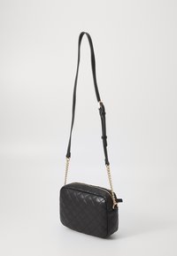 Bolso cruzado de cuero negro acolchado con forma rectangular, detalles en cadena dorada y una correa ajustable negra. Cierre superior con cremallera.