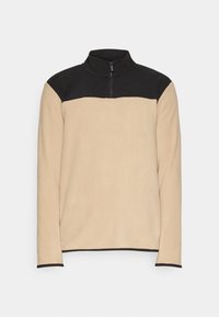 Sudadera de felpa beige con un panel negro en los hombros, cuello alto y cremallera de un cuarto en la parte delantera. Presenta un ribete negro en los puños.
