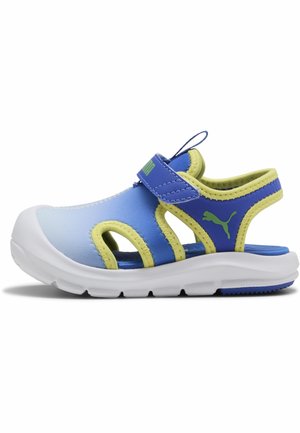 Sandale pour enfants bleu et jaune avec embout fermé, bride ajustable, semelle blanche coussinée et logo Puma sur le côté.
