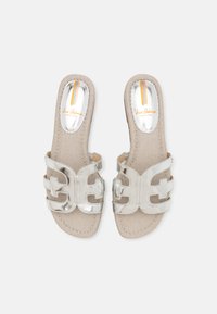 Sandales à enfiler métalliques argentées avec un design croisé, semelle beige texturée et intérieur réfléchissant avec des rayures orange.