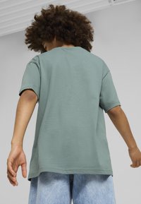 Camiseta de algodón verde claro con manga corta, corte relajado y cuello redondo, combinada con pantalones cortos de mezclilla azul claro.