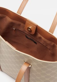Beige tote bag with a textured pattern, light brown synthetic straps, magnetic snap closure, and an interior zip pocket.