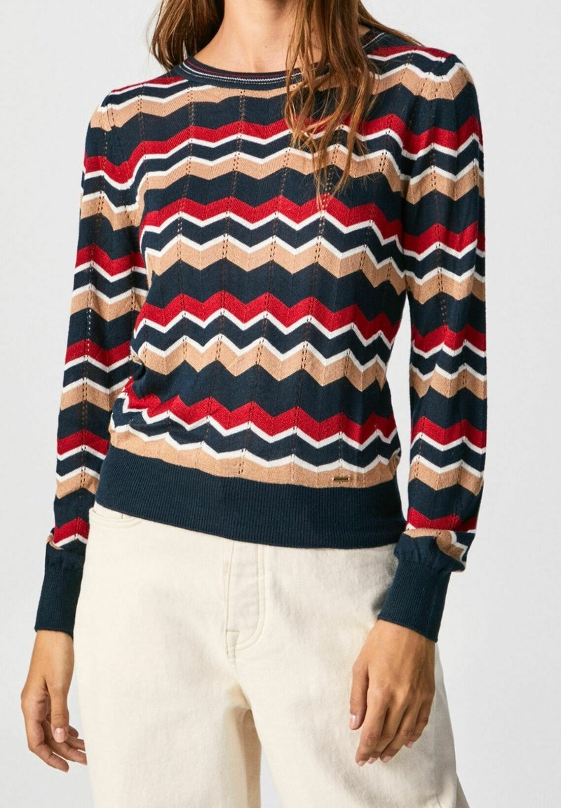 Pletený svetr s cikcak vzorem v námořnické modři, červené, béžové a bílé barvě. Žebrované manžety a lem s průhledným vzorem po celém svetru.