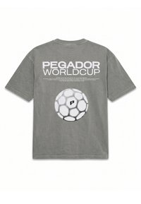Γκρι μπλουζάκι με μεγάλο λευκό κείμενο "PEGADOR WORLD CUP" και ένα στυλιζαρισμένο γραφικό ποδοσφαιρικής μπάλας κάτω από το κείμενο στην πλάτη.