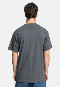 Graues Kurzarm-T-Shirt mit strukturiertem Material und lässiger Passform, das auf der Rückseite ein dezentes Logo trägt.