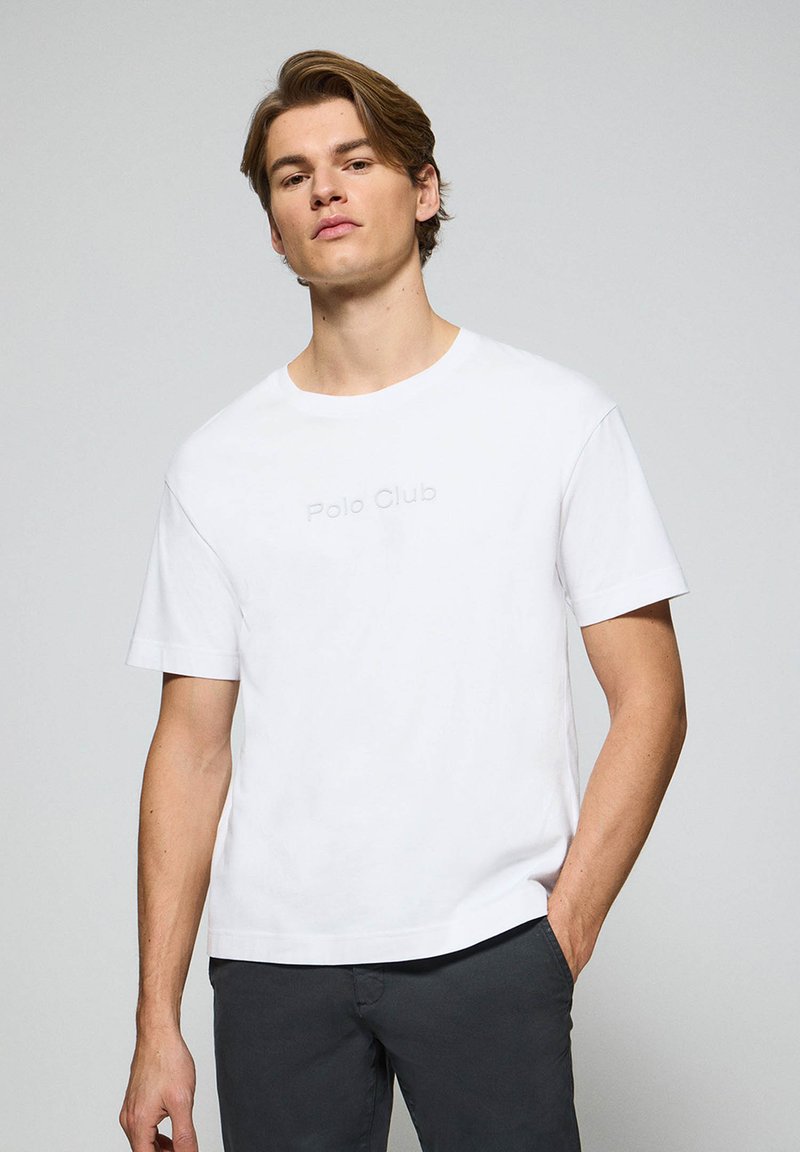 Biała bawełniana koszulka z krótkimi rękawami, z wytłoczonym napisem "Polo Club" z przodu oraz luźnym dekoltem typu crew neck. Klasyczny krój.