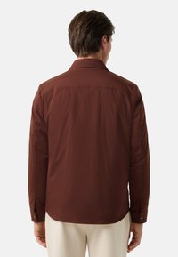 Braune, leichte Jacke mit langen Ärmeln, glatter Textur, Knopfmanschetten und klassischem Kragen, von hinten gezeigt.