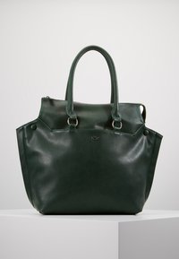 Ciemnozielona skórzana torba na ramię z podwójnymi uchwytami na górze, srebrnymi pierścieniami łączącymi uchwyty oraz małym metalowym logotypem umieszczonym na środku przodu.