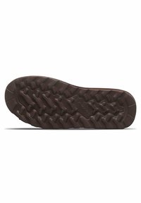 Semelle en caoutchouc avec des reliefs profonds pour l'adhérence, de couleur marron, surface texturée et motif en zigzag distinct pour la traction.