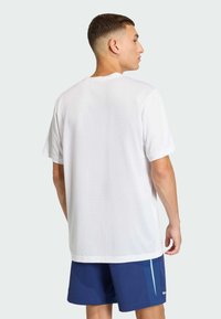 Witte T-shirt met korte mouwen, in een relaxte pasvorm en zachte textuur, gecombineerd met blauwe shorts met lichtere zijaccenten en een gladde afwerking.