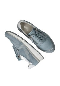 Light blue sneakers made of suede and leather, featuring a textured design, silver accents, and a white rubber sole with a black tread.
