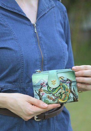 Grünes Lederportemonnaie mit einem Drachendesign zwischen Kirschblüten und Bergen, mit einem goldenen Blumenakzent und Reißverschluss.