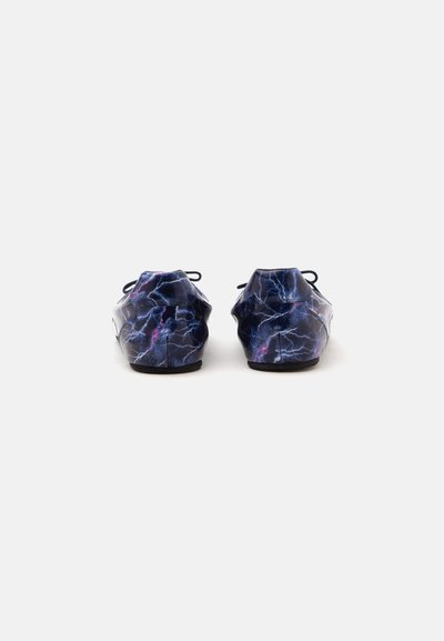 Paire de baskets foncées avec un motif d’éclairs bleu et violet vues de dos sur un fond blanc uni.