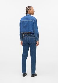 Gecropt spijkerjack en spijkerbroek met rechte pijpen in medium blauw. Het jack heeft knoopmanchetten en contrasterende stiksels. De jeans hebben achterzakken.