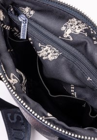 Modrý zippered batoh uvnitř s vzorovanou tkaninou, která obsahuje grafiku bílého jezdce. Obsahuje více kapes a pevný zip.