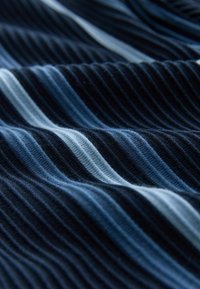 Tekstūruota medžiaga su pakaitinėmis tamsiai mėlynomis ir šviesiai mėlynomis juostelėmis, turinti šonkaulinį raštą, kuris pabrėžia jos tekstūrinę savybę.