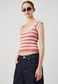 Top court à rayures roses et blanches avec un décolleté carré, en tissu texturé, associé à un jean taille haute bleu foncé avec poches.