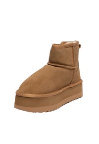 Stivale alla caviglia in suede marrone con punta arrotondata, altezze intermedie e suola piatta spessa. Interno morbido foderato e cuciture a vista.