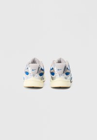 Γκρι και μπλε αθλητικά παπούτσια με υφή στην επιφάνεια, αντανακλαστικές ασημί λεπτομέρειες και κρέμ σόλα. Διαθέτουν επένδυση στον γιακά και λεπτομέρειες από δίχτυ.