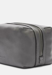  neceser de cuero gris con forma rectangular, textura suave y cierre de cremallera en la parte superior. Presenta un sutil logotipo grabado en el costado.