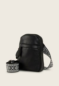 Sac en cuir noir à bandoulière, avec une sangle noire et blanche à motifs, doté d'une fermeture éclair et d'une poche frontale. Comprend un accessoire de sangle assorti.