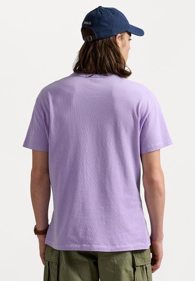 Lila bomullströja med korta ärmar. Lätt texturerad, avslappnad passform. Kombineras med olivgröna cargoshorts och en marinblå keps.