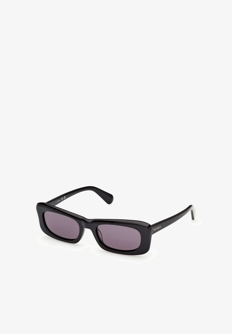 Lunettes de soleil rectangulaires noires avec des verres foncés et des branches fines, présentées en angle sur un fond blanc.