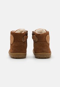 Hnědé semišové kotníkové boty s měkkým interiérem, vybavené bočními zipy a kulatými detaily. Texturované gumové podrážky pro lepší přilnavost a odolnost.